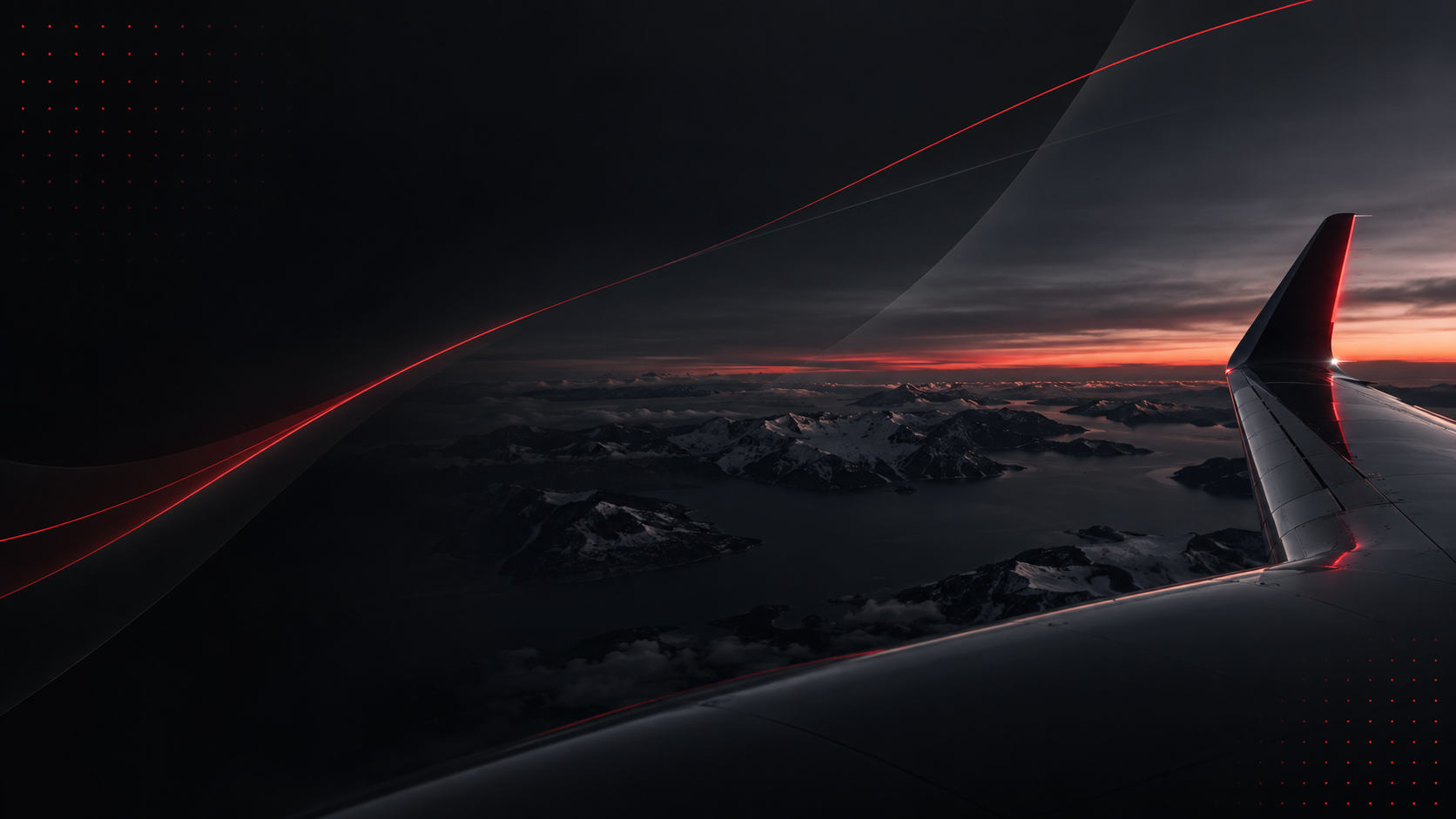 View of an aircraft wing at dusk over mountains and coastline.